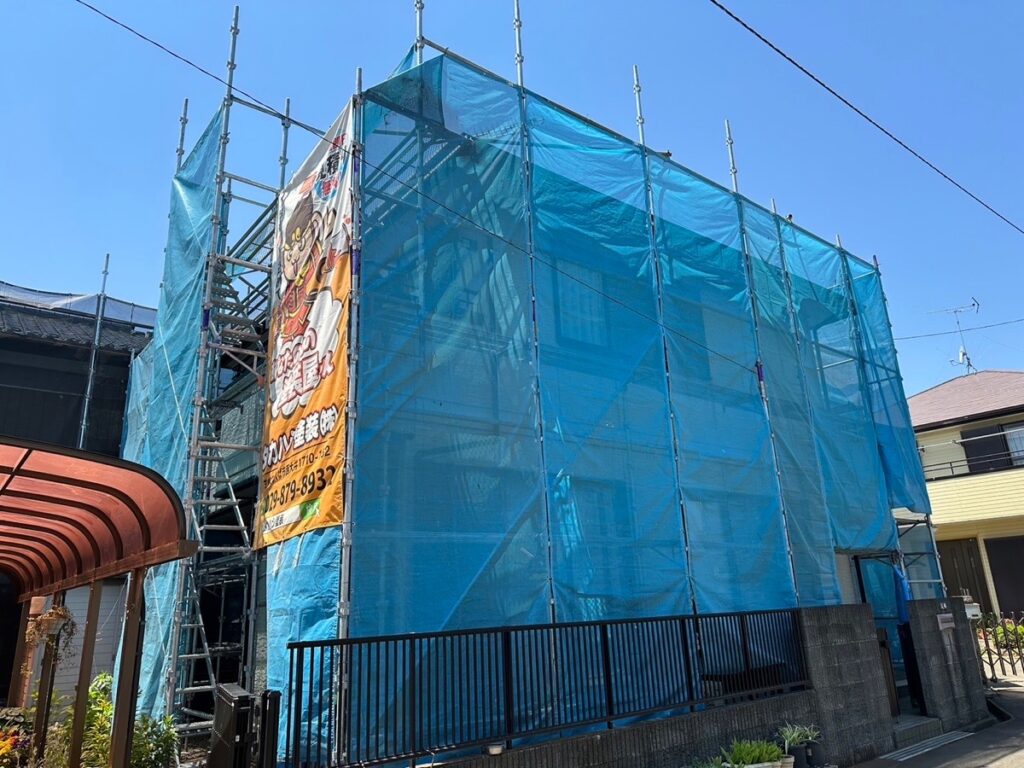 足場組立<br />
（塗料が飛散しないようにメッシュシートをしっかりと貼りました。）