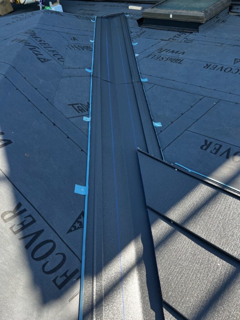 谷板金取り付け<br />
（屋根と屋根が重なり合う所を谷板金といいます。雨漏れがしやすい箇所の為、直接本体にビス打ちをせず、横に捨て板金をつけ、ビスで谷板金を固定しています。）