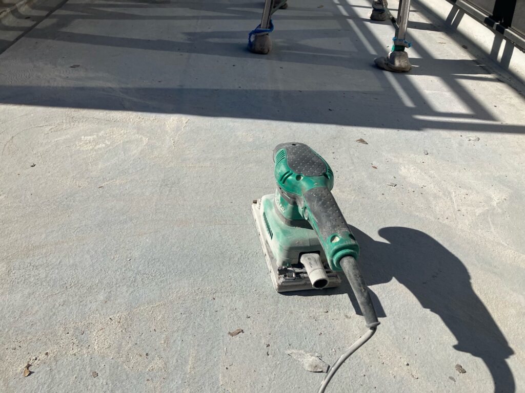 下地調整<br />
（既存の防水層の剥がれがあるため、電動工具を使用し、下地を整えました。）