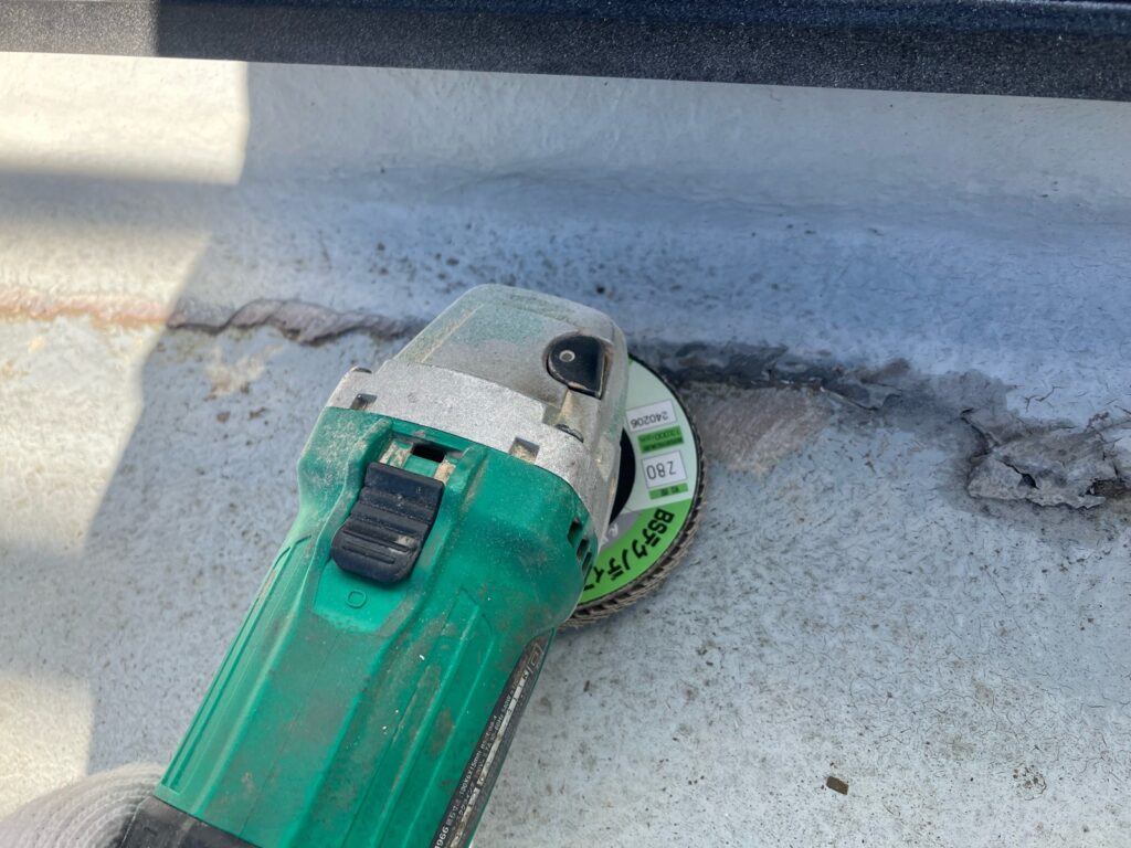 下地調整<br />
（既存の防水層の剥がれがあるため、電動工具を使用し、下地を整えました。）