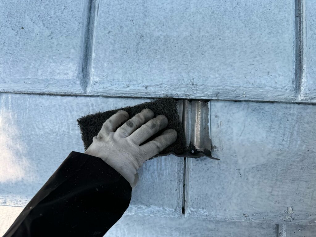 棟板金ケレン<br />
（ケレンとは、塗料との密着を良くするために、専用の道具で細かい傷をつける下地調整です。）