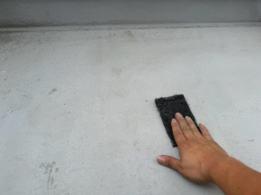 ベランダ床ケレン<br />
（ケレンとは、塗料との密着を良くするために、専用の道具にて細かい傷をつける下地調整です。）