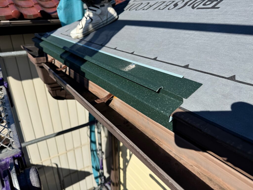 唐草スターター取り付け<br />
（屋根カバー工事の際に一番最初に取り付ける金物です。）<br />
<br />
※既存の雨どいを交換しなくても雨水が雨どいに流れるように、セットバックスターターという唐草を使用しています。通常の唐草でカバー工法を行うと、雨水が雨どいに流れなくなる可能性があります。