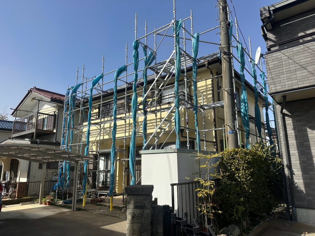 足場組立<br />
（足場当日が風が強かった為、飛散防止シートは一旦束ね、後日シートを復旧しました。）
