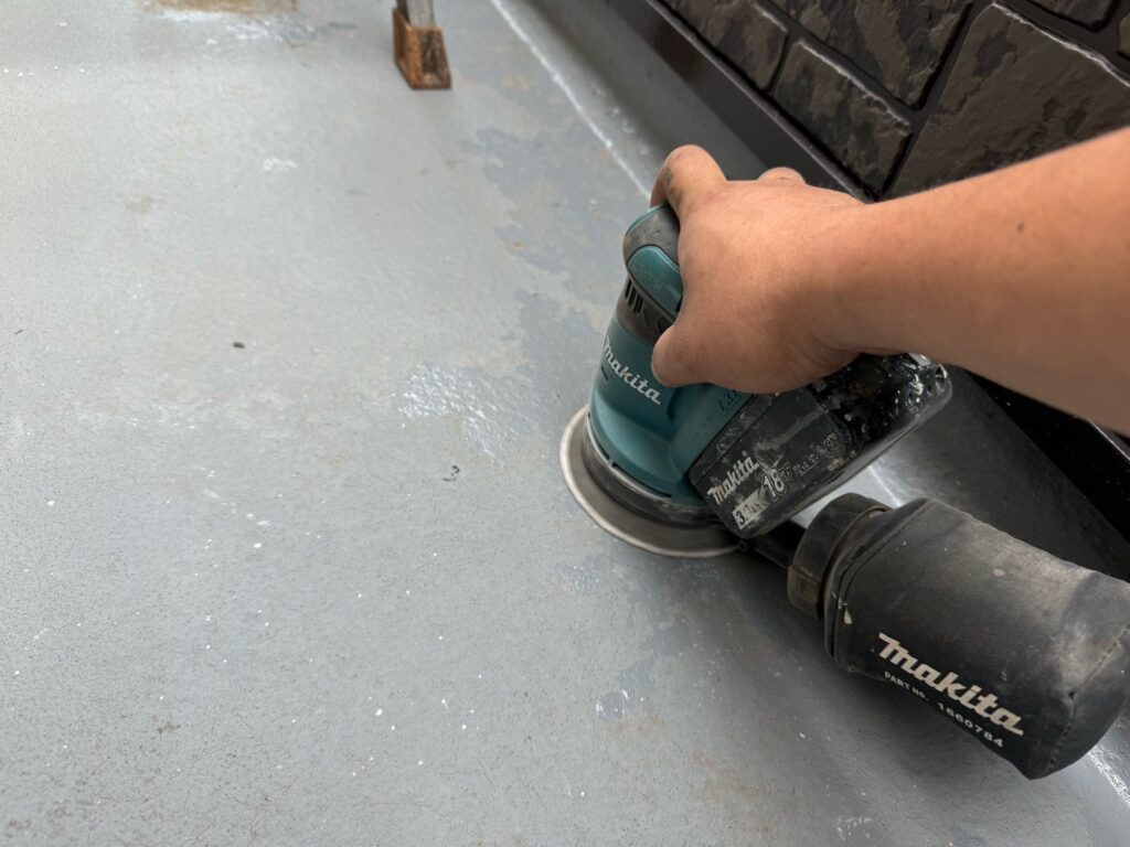 ベランダ床ケレン<br />
(ケレンとは、塗料との密着を良くするために、専用の道具にて細かい傷をつける下地調整です。)